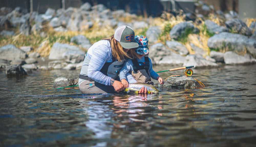 幼いLochlanを背負って川の浅瀬にかがみ、魚を扱うAmber Toner