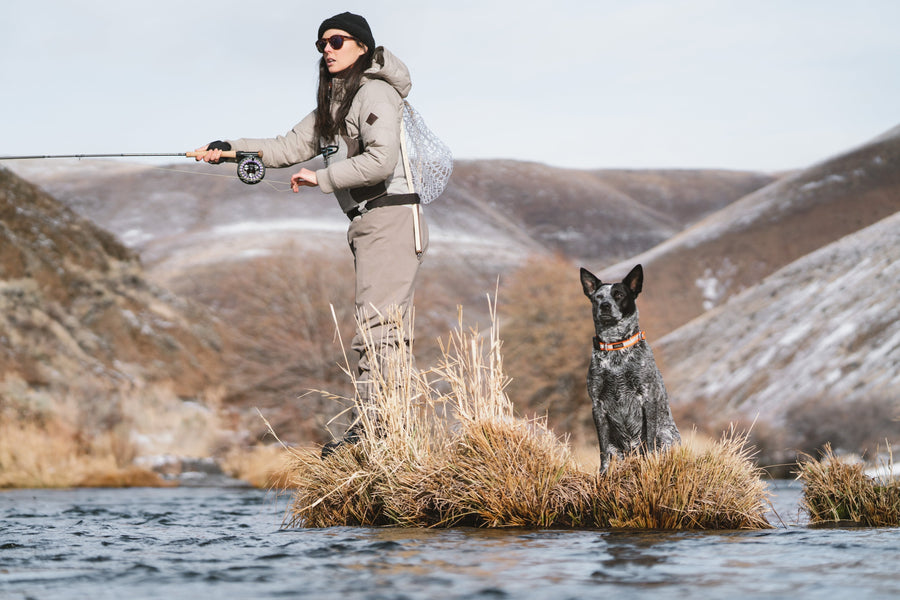 川の中の草の小島に愛犬と立ち、キャストするKayla Lockhart