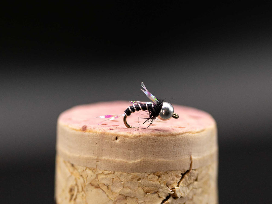 コルクの上に置かれたビーズヘッドのCrackleback Midge